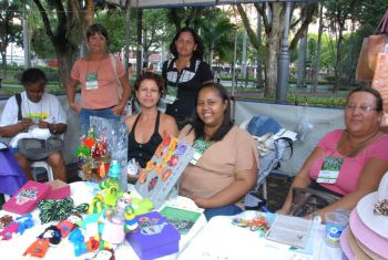 Mulheres ao lado de sua produção de artesanato com fuxico, crochê e bolsas de lona, entre outras
