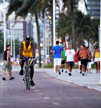 Ciclista e pessoas caminhando no calcação da Praia de Camburi