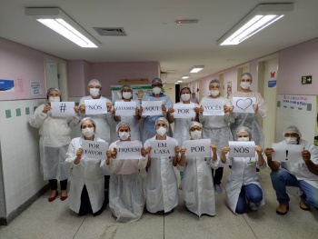 Equipe de saúde da unidade do Quadro segura cartazes onde pede para a população ficar em casa