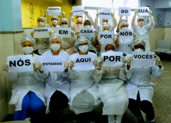 Equipe de saúde da unidade da Praia do Suá segura cartazes onde pede para a população ficar em casa