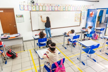 Sala de aula com professora e alunos respeitando o distanciamento e protocolos Covid-19