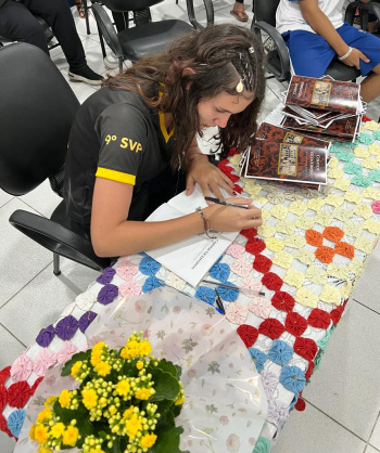 Estudante escritora autografa livro de contos da Emef São Vicente de Paulo