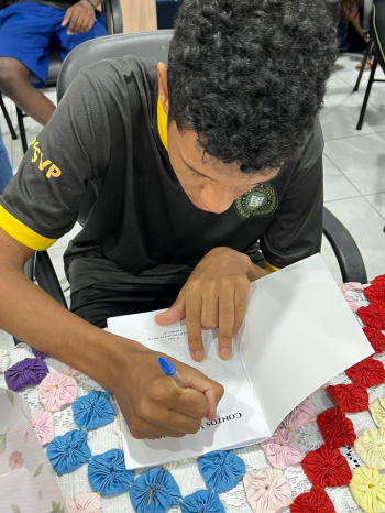 Estudante escritor autografa livro de contos da Emef São Vicente de Paulo